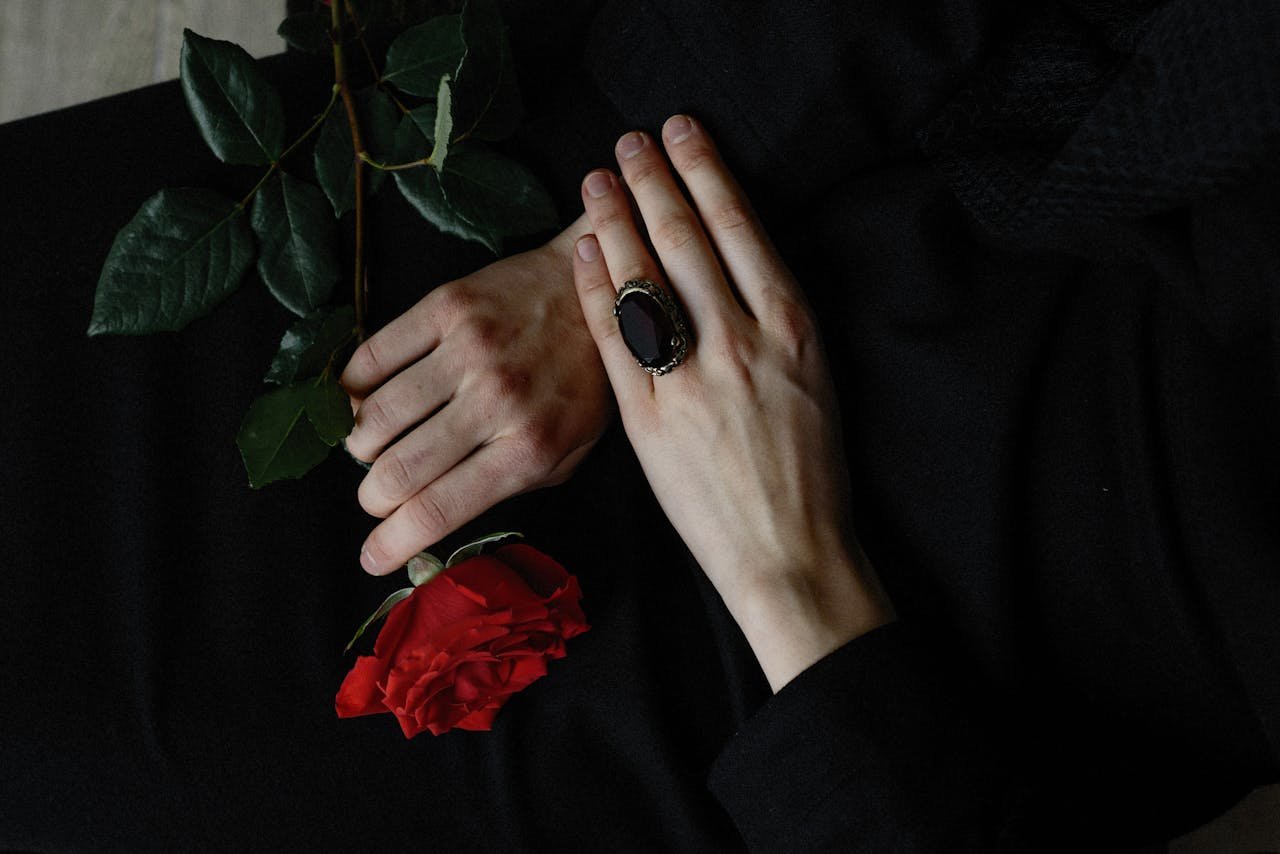 A touching close-up photo of hands holding a red rose, symbolizing loss at a funeral.
